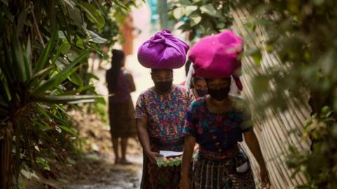 Women carry aid supplies donated by the municipality after the restriction measures ordered by the Government to prevent the spread of coronavirus at El Hato, in Antigua Guatemala, Guatemala, 25 April 2020