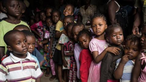 Children staying in the half built house queue up to receive clothes donated by some Lebanese women who live in Freetown