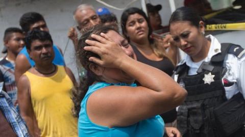 Relatives of five people murdered on a street cry in Acapulco's Icacos neighbourhood