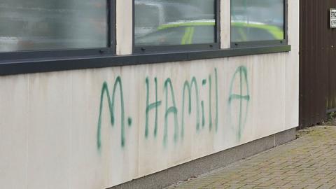 Green graffiti with M Hamill with a target symbol is sprayed outside of Newtownards court