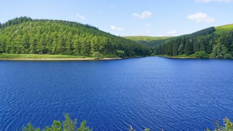 Over the breadth of Derwent Upper Reservoir to the wooded hills of Derbyshire