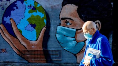 A pedestrian on the Taff Trails passing the street art painted Thomas Llewelyn reminding people passing by that the battle against Coronavirus is still ongoing and to wear masks on January 22, 2021