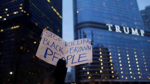 Placard saying "stop killing black and brown people" in front of Trump tower