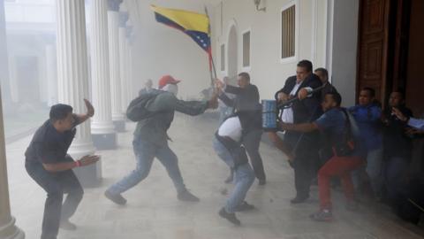 A goverment supporter holds a National flag while clashing with people outside Venezuela"s opposition-controlled National Assembly, in Caracas, Venezuela July 5, 2017.