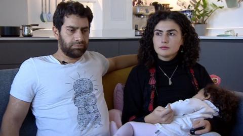 Imad Alqasim and Zeina Ramadan sat on a sofa with their young daughter.