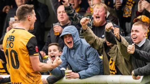 Leamington players celebrate with their fans after winning promotion to National League North
