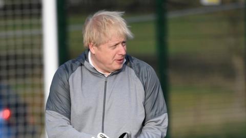 British Prime Minister Boris Johnson puts on goalkeeping gloves before a girls" soccer match during an election campaign event on December 7, 2019 in Cheadle Hulme, United Kingdom