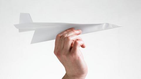 Hand holding paper aeroplane