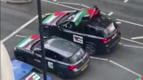A grab from the video filmed and shared on social media, it shows two cars parked at traffic lights with Palestinian flags