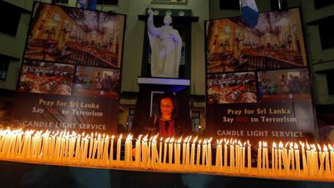 A woman lights a candle during a vigil to show solidarity with the victims of Sri Lanka's serial bomb blasts