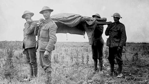 Allied forces carrying a dead soldier on a stretcher during the World War One Battle of the Somme