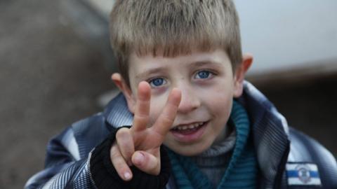 A Syrian child, who was among the people evacuated from Kafarya and Fuah villages of Idlib province, flashes the victory sign upon arriving at a temporary housing center in Jebrin, Aleppo countryside