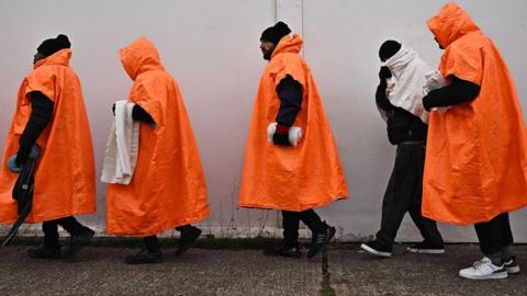 Migrants standing in a queue waiting to be processed in Kent.