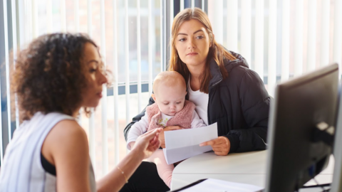 An adviser speaking to a woman holding a baby