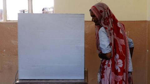 An Indian voter stands near a voting machine at a polling station booth at Dabua village on the outskirts of Faridabad on April 10, 2014