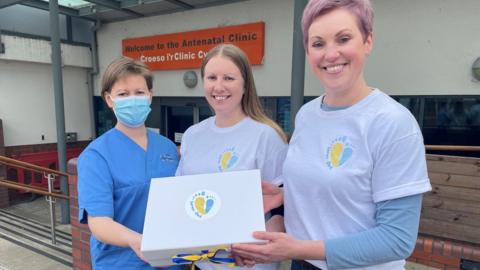 Laura Thomas and Lou Kennedy presenting the box to Anna Griffiths at University Hospital of Wales in Cardiff