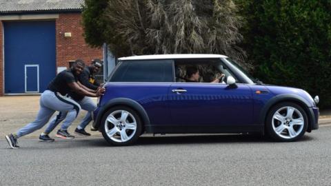 Bobsleigh team members pushing car