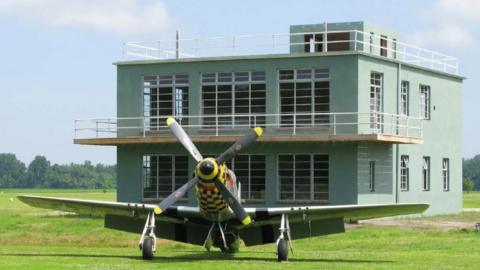 Green building with a WWII aircraft stationed in front