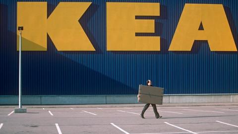 Man walking with a box infront of ikea sign