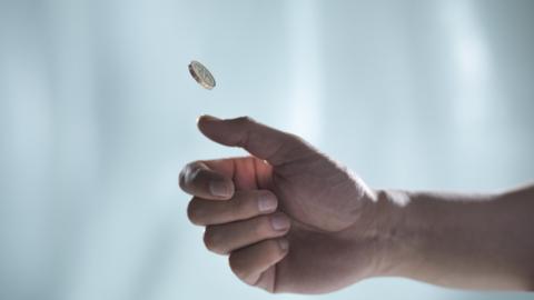 A hand flipping a coin