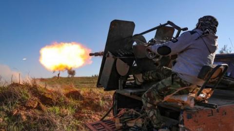 A Turkey-backed Syrian fighter fires a lorry-mounted gun in Idlib. Photo: February 2020