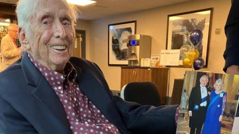 Jack Glover with a portrait of King Charles and Queen Camilla