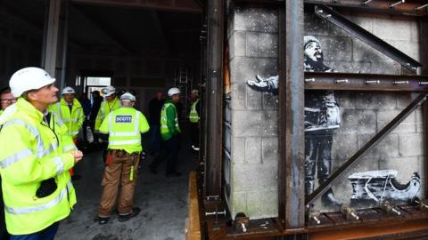 Contractors inspect the Banksy