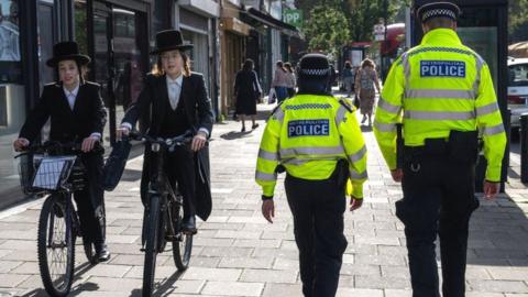 Orthodox Jewish men pass police officers as they patrol around Stamford Hill, an area of London with a large Jewish community, on October 10, 2023 in London, England.