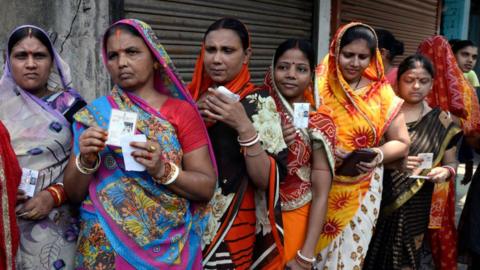 Indian women hold Voter ID cards and stand in queue to cast their vote at polling station during the last phase of Lok Sabha Election.