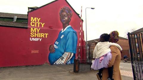 Maimuna Indjai looking at her mural