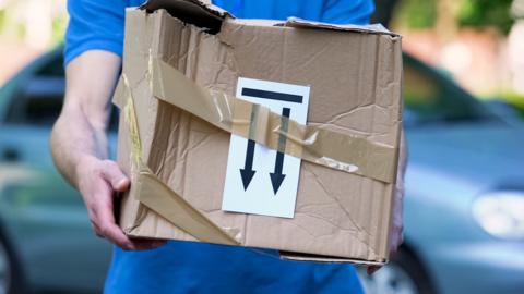 A delivery worker holding a broken parcel