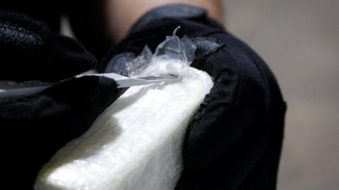 A file photo shows an agent cutting open a brick of cocaine seized by US customs officials in June 2019