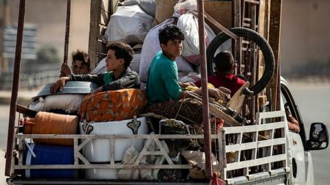 Displaced Syrians sit in the back of a truck as Arab and Kurdish civilians flee amid Turkey's military assault on Kurdish-controlled areas in north-eastern Syria, on October 11, 2019 in the Syrian border town of Tal Abyad