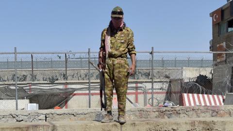 A Taliban fighter stands at the site of the attack at Kabul airport on 27 August 2021