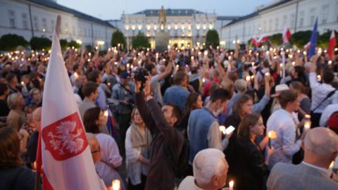 Protesters hold candles in front of the Presidential Palace in Warsaw, Poland, 18 July 2017