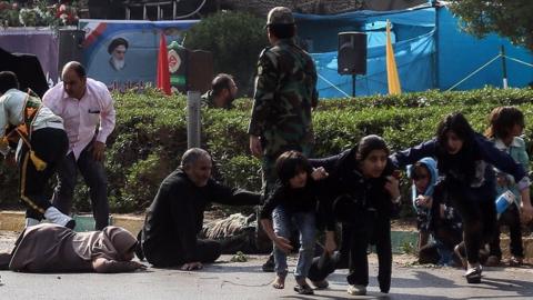 Iranian soldiers, women, and children lay down and run during the attack