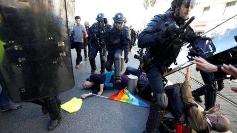 People lay on the ground as riot police try to disperse the crowd at a French "yellow vests" protest in Nice on 23 March 2019