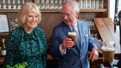 LONDON, ENGLAND - MARCH 15: Prince Charles, Prince of Wales holds a pint of Guinness he has poured as he stands next to Camilla, Duchess of Cornwall during a visit to The Irish Cultural Centre on March 15, 2022 in London, England. The Prince of Wales and The Duchess of Cornwall visited the Irish Cultural Centre to celebrate the Centres 25th anniversary in the run-up to St Patricks Day. (Photo by Arthur Edwards - WPA Pool/Getty Images)