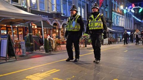 Two South Wales Police officers in uniform and helmets patrol bars area in Cardiff city centre after firebreak lockdown ends and venues reopened in November