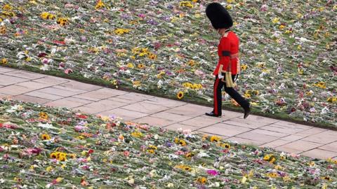 A King's Guard soldier walks along the lawn covered with flowers at the Windsor Castle