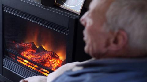 Elderly man in front of fire