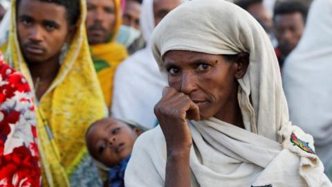 A woman stands in line to receive food donations, at the Tsehaye primary school, which was turned into a temporary shelter for people displaced by conflict, in the town of Shire, Tigray region, Ethiopia, March 15, 2021