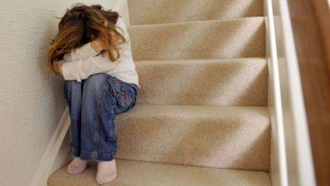 Girl hiding face sat on stairs