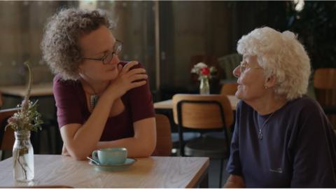 Two women talking over a cup of tea in a cafe