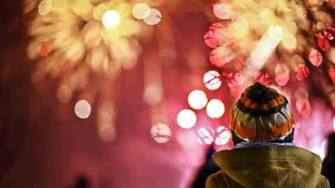 A child in the foreground watching aa fireworks display.