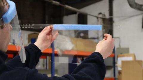 ICL worker checks a visor during production process