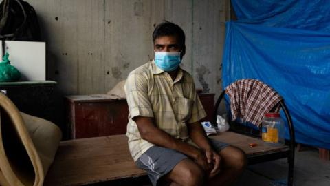 A migrant worker sits on his bed in a construction site on 17 May 2020 in Singapore