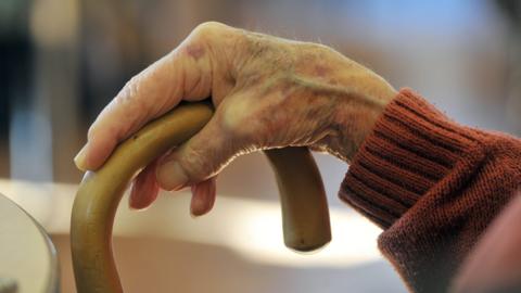 Elderly man's hand holding walking stick