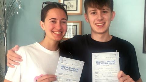 Twins holding up their driving test certificates