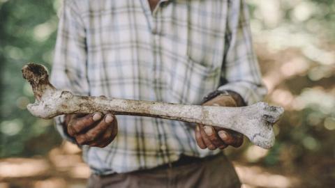 Ramiz holds a human bone.